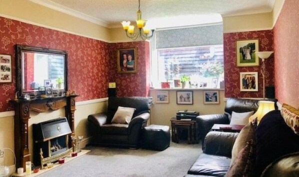 A living room with a fireplace, leather sofas, and a chandelier. - promenade pleasure beach and short 5 minutes walk to the football ground.all ro. (Blackpool)