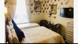 Une chambre d’hôtel avec deux lits, une télévision, une commode et une fenêtre avec des rideaux.