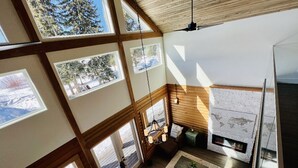 Un amplio salón con ventanas grandes, chimenea y una zona de estar acogedora.
