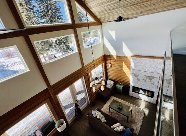 A spacious living area with large windows, a fireplace, and a cozy seating arrangement.
