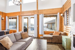 A log cabin interior with a sofa, armchair, and a dining table.