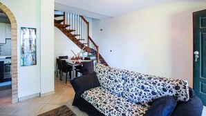 A living room with a sofa, a dining table with chairs, and a staircase leading to another room. - Lovely home in Porto Recanati with WiFi (Porto Recanati)