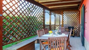 A covered outdoor dining area with a wooden table and chairs, a bench, and a lattice fence. - Lovely home in Porto Recanati with WiFi (Porto Recanati)