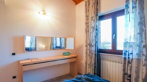 A bedroom with a bed, a bedside table, a mirror, a window with curtains, and a thermostat on the wall. - Lovely home in Porto Recanati with WiFi (Porto Recanati)