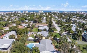 Zona residencial com casas, palmeiras e vista clara para o oceano.