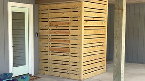 A room with a wooden slat partition, a white door, and a concrete floor.