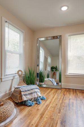 A room with wooden flooring, a large mirror, and a woven pouf. - TWO king bedrooms! Walk to EVERYTHING! (lake,hiking,bars,shopping) (Watkins Glen)