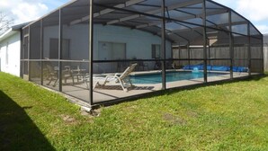 Ein Pool mit Umzäunung und überdachter Terrasse, inklusive Pool und Gartenmöbeln.