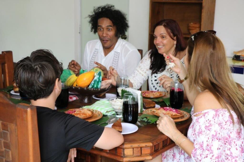 Un gruppo di persone cena a un tavolo di legno, con diversi piatti e bevande.