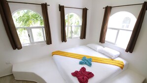 A hotel room with a bed, curtains, and windows.
