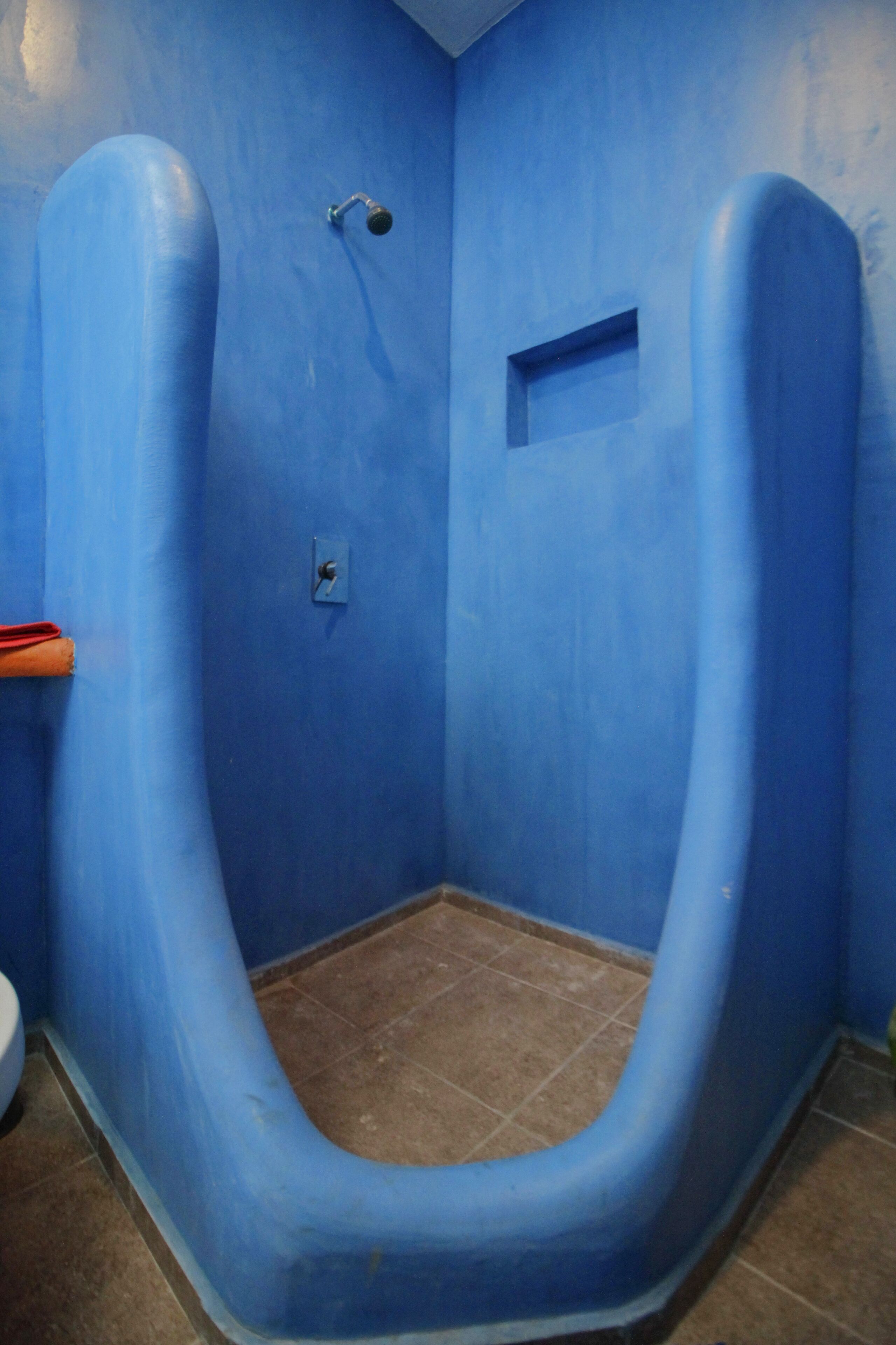 A bathroom with a blue shower enclosure and a small window.