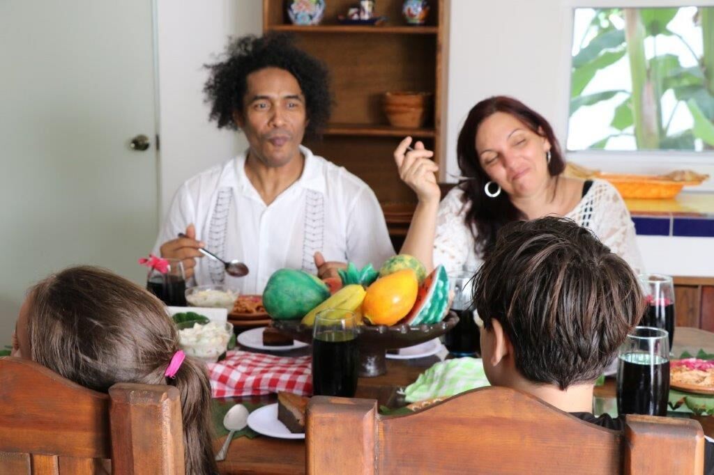 A family dining at a wooden table with a variety of fruits and vegetables.
