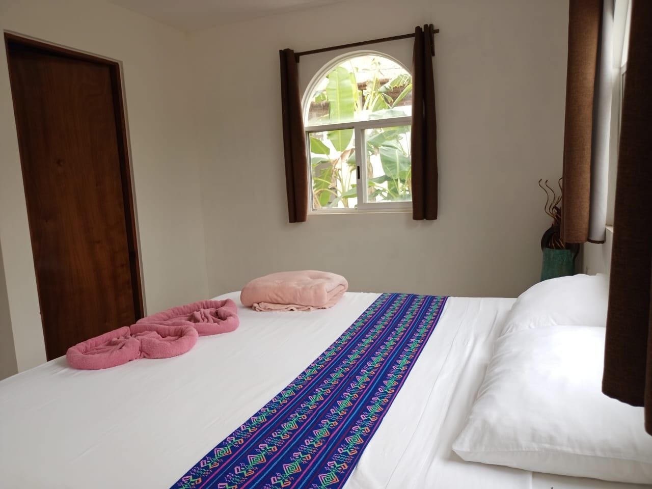 A bedroom with a bed, a window, and a door.