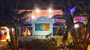 A building with a colorful mural on the facade, surrounded by tropical vegetation.