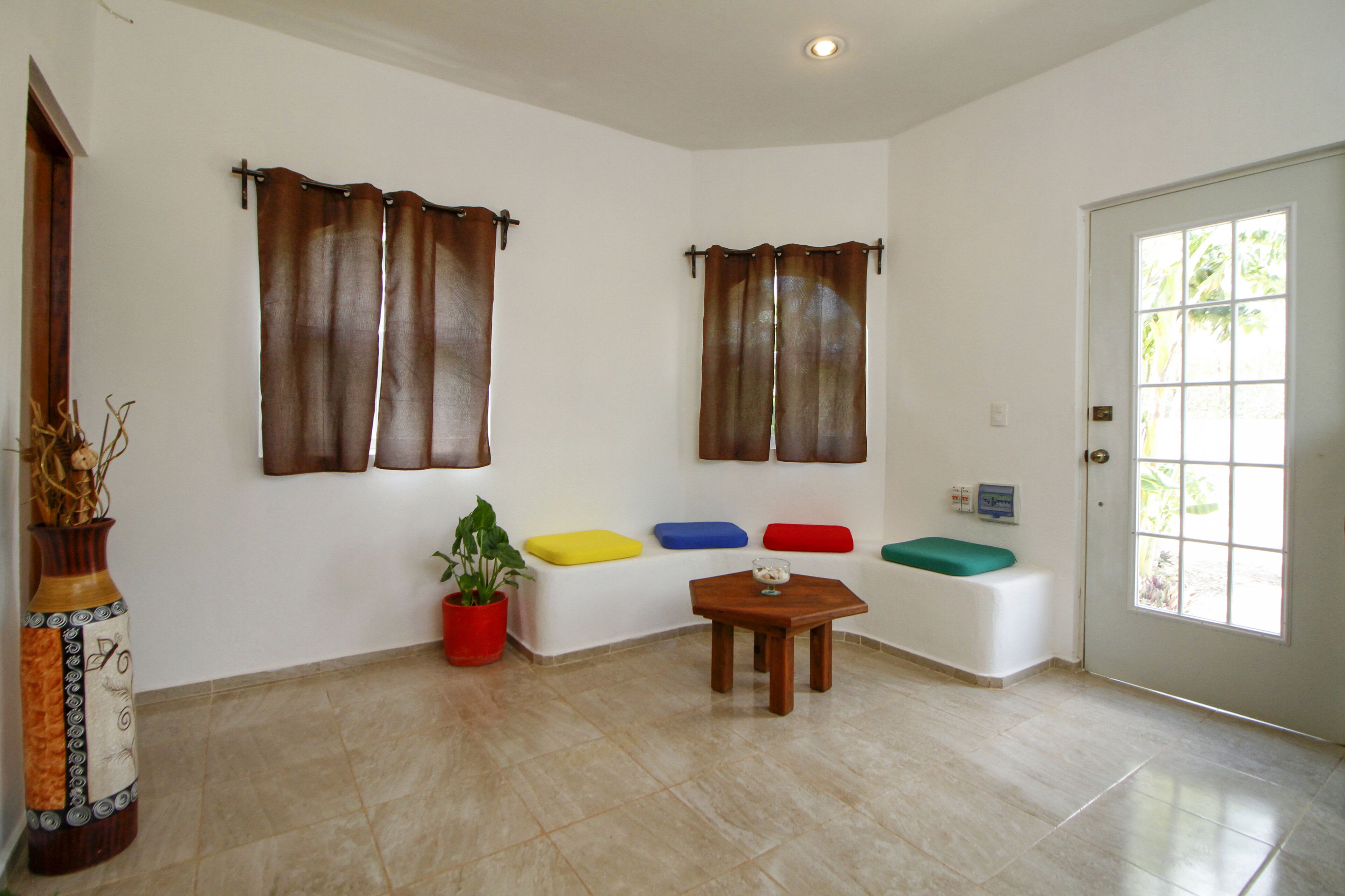 Un amplio espacio de sala con un conjunto de sofá blanco, una mesa de centro de madera y una planta en maceta.
