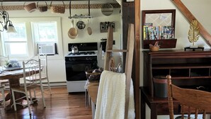 A cozy kitchen with wooden beams, a dining area with a wooden table and chairs, and a staircase with a wooden railing.