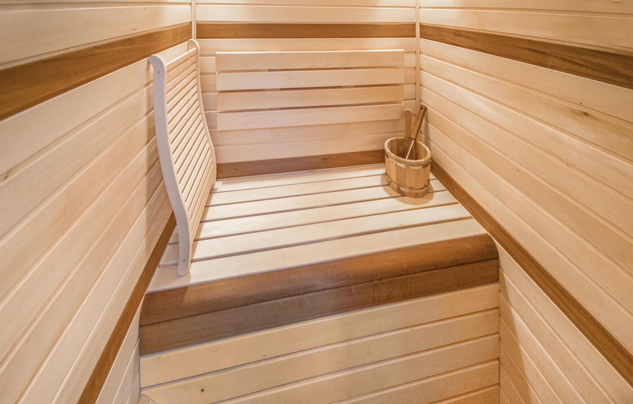 A sauna with wooden benches and a white towel rack.