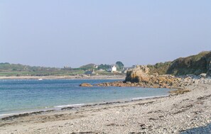 A coastal beach with pebbly shore, a rocky outcrop, and houses in the background. - 2 bedroom amazing home in Pleubian (Pleubian)