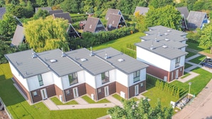 Ein moderner Wohnkomplex mit mehreren zweigeschossigen Häusern, jedes mit flachem Dach und einer Fassade in Weiß- und Brauntönen.