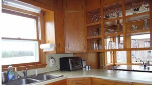 Una cocina con armarios de madera, un lavamanos, un tostador y una ventana con vistas.