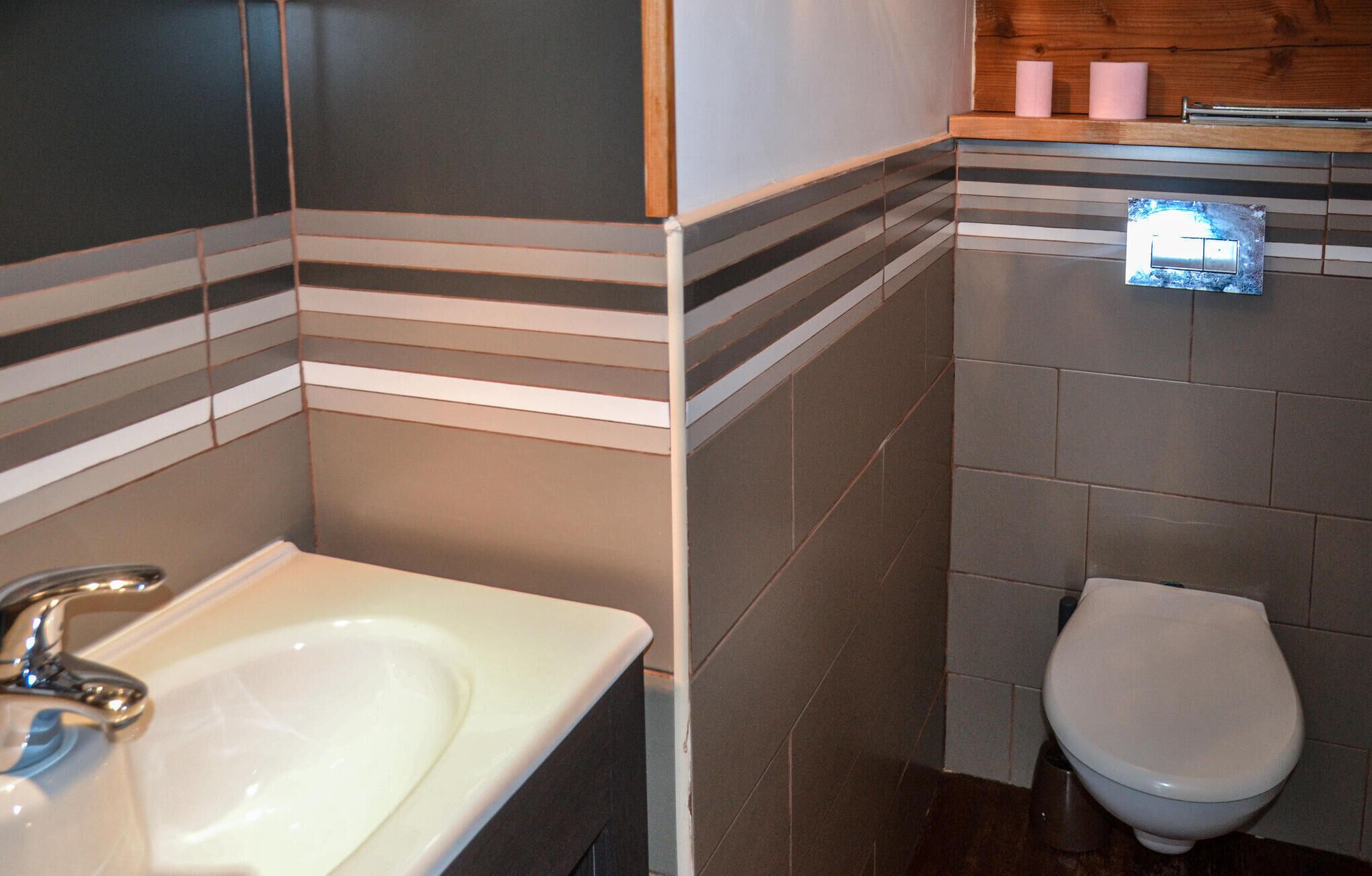Une salle de bain avec un lavabo blanc, des toilettes et un miroir.