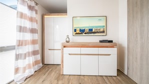 A modern room with a wooden floor, white cabinets, a framed picture of a beach scene, and a striped curtain. - Amazing home in Damp with sauna (Damp)