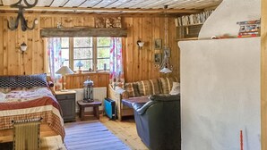 Kodikas, mökin tyylinen huone, jossa on sänky, sohva, pieni pöytä ja patteri.
