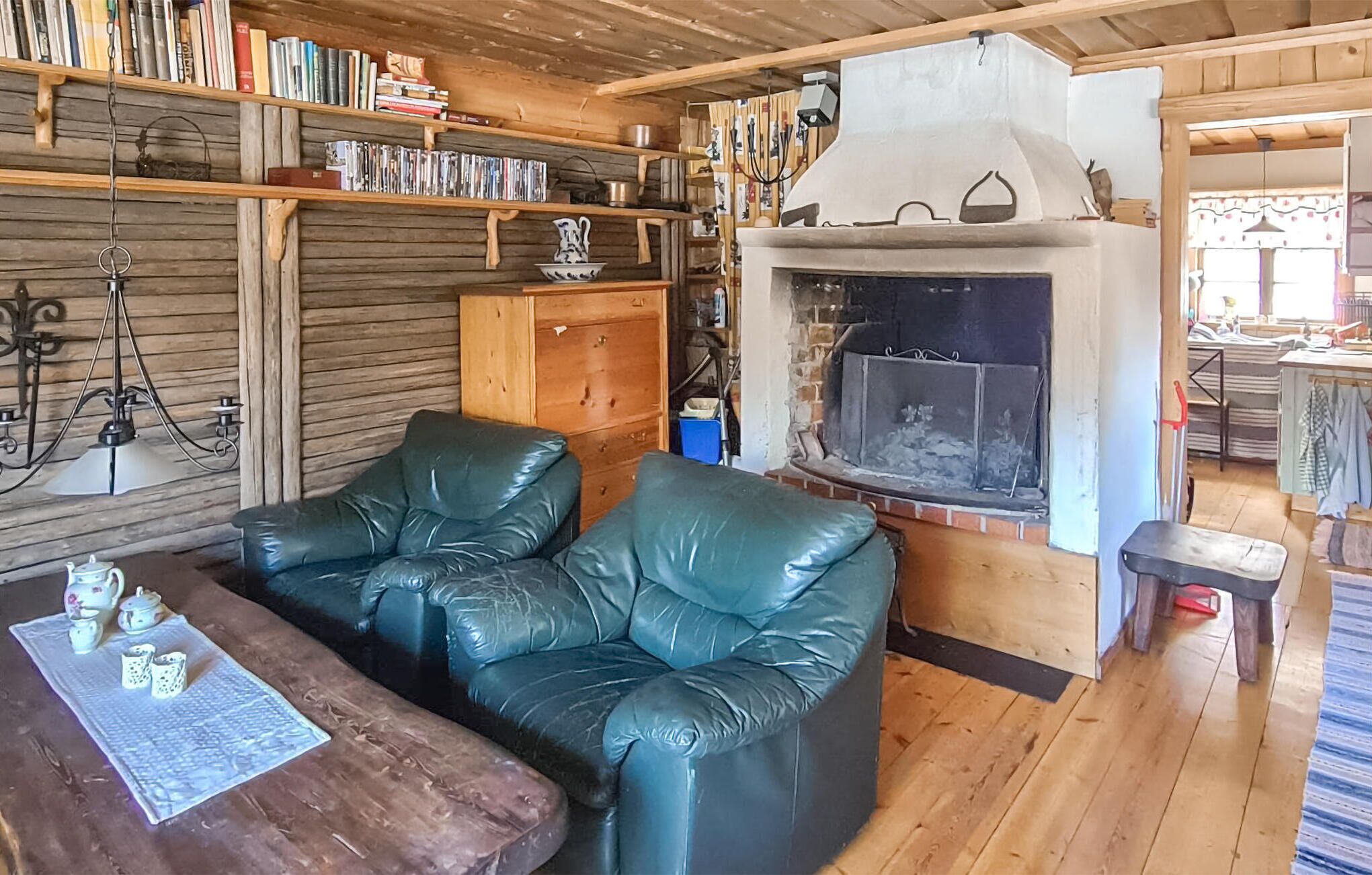Un salon chaleureux avec une cheminée, des canapés en cuir, des étagères en bois remplies de livres et une table basse en bois.