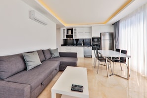 A modern living room with a grey sofa, a white coffee table, and a dining area with a white table and chairs. - Spacious, Comfortable 1 Bed Private Villa with the most fabolous Kalkan BayViews (Antalya)