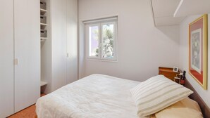 Une chambre à coucher avec un lit, une fenêtre, une armoire et un tableau encadré au mur.