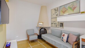 Un salon comprenant un canapé, des fauteuils, un téléviseur et des dessins d’architecture encadrés accrochés au mur.