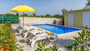 A swimming pool with white lounge chairs and a yellow umbrella. - Luxurious home in Pomer (Pomer)