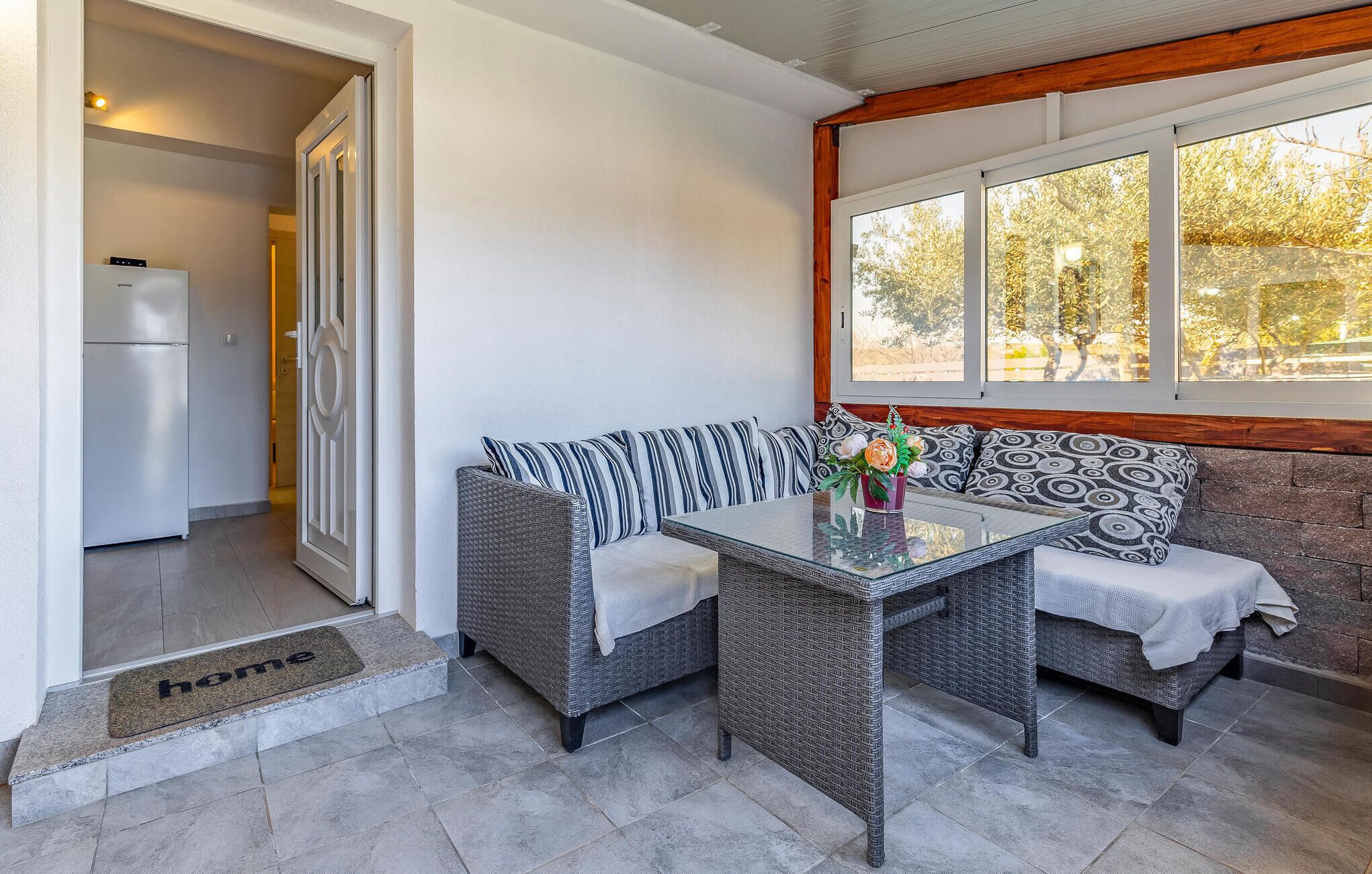 A modern kitchen with a built-in refrigerator and a dining area with wicker furniture and a glass table.