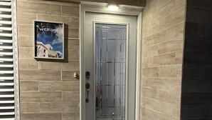 A modern entrance with a glass door, a welcome sign, and a tiled porch. - Great location! Marco Island home with pool that’s just 2miles to beaches (Marco Island)