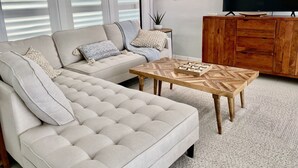 A living room with a sofa, coffee table, TV, and wooden cabinet. - Great location! Marco Island home with pool that’s just 2miles to beaches (Marco Island)