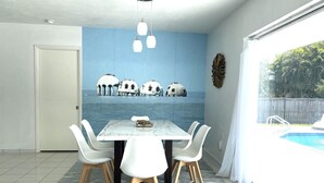 A dining area with a marble table, white chairs, and a view of a pool through a glass door. - Great location! Marco Island home with pool that’s just 2miles to beaches (Marco Island)