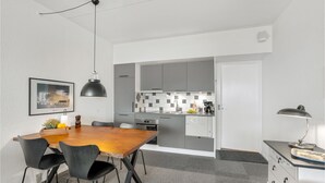Una cocina compacta con electrodomésticos modernos, un comedor con mesa y sillas de madera, y una pequeña zona de cocina.