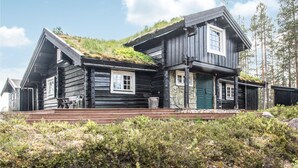A log cabin with a stone foundation, a green door, and a thatched roof.