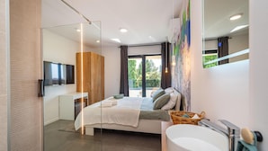 Quarto moderno com cama, mesa de cabeceira e uma janela grande.