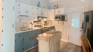 A kitchen with white and blue cabinets, a microwave, a refrigerator, and a wooden island. - The Tree House! (Florence)