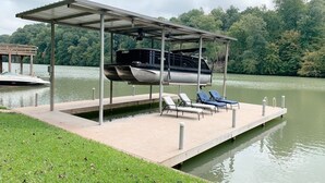 A covered boat dock with lounge chairs and a boat. - The Tree House! (Florence)
