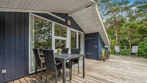 A deck with a table and chairs, a grill, and a view of the surrounding trees.