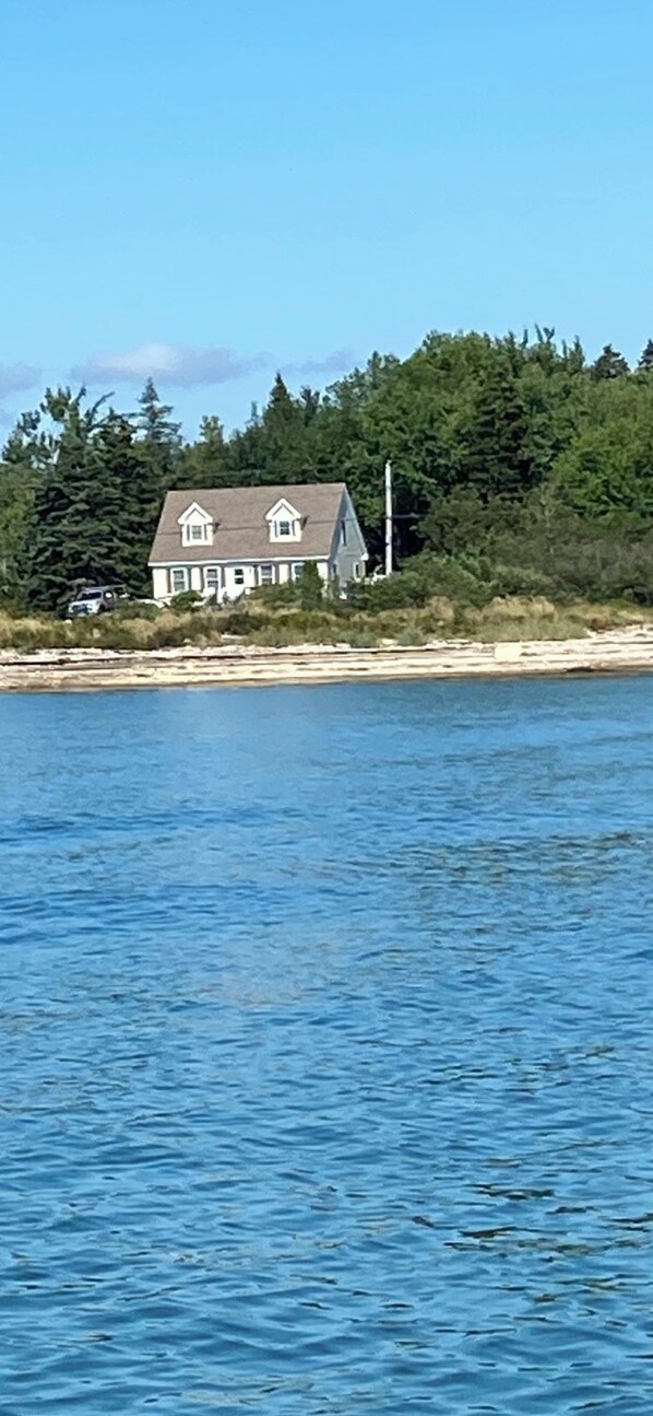 A house by a body of water with a clear sky.