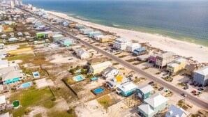 Vista aérea de una zona residencial costera con casas, una playa y una carretera.
