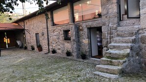 Um edifício de pedra com um pátio, garagem e uma pequena janela com plantas.