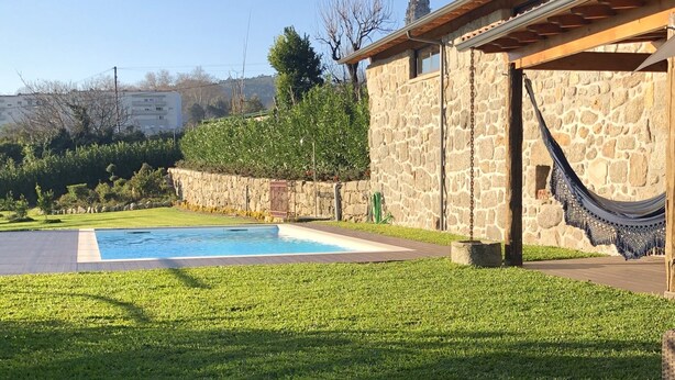 Uma área de pátio com móveis de vime, uma parede de pedra e uma piscina.