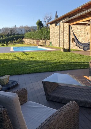 A patio area with wicker furniture, a stone wall, and a pool.