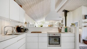 A modern kitchen with white cabinetry, a stainless steel sink, a coffee maker, and a built-in oven. - Nice home in Hornbæk with kitchen (Hornbæk)