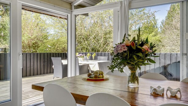 An outdoor dining area with a wooden table, white chairs, and a vase of flowers. - Nice home in Hornbæk with kitchen (Hornbæk)