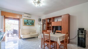 A dining area with a table set for four, a sofa, and a cabinet with shelves. - Pet friendly apartment in Carovigno (Carovigno)